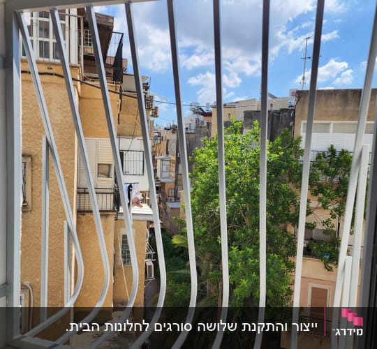 סורגים לבנים בחלון עם נוף עירוני ברקע